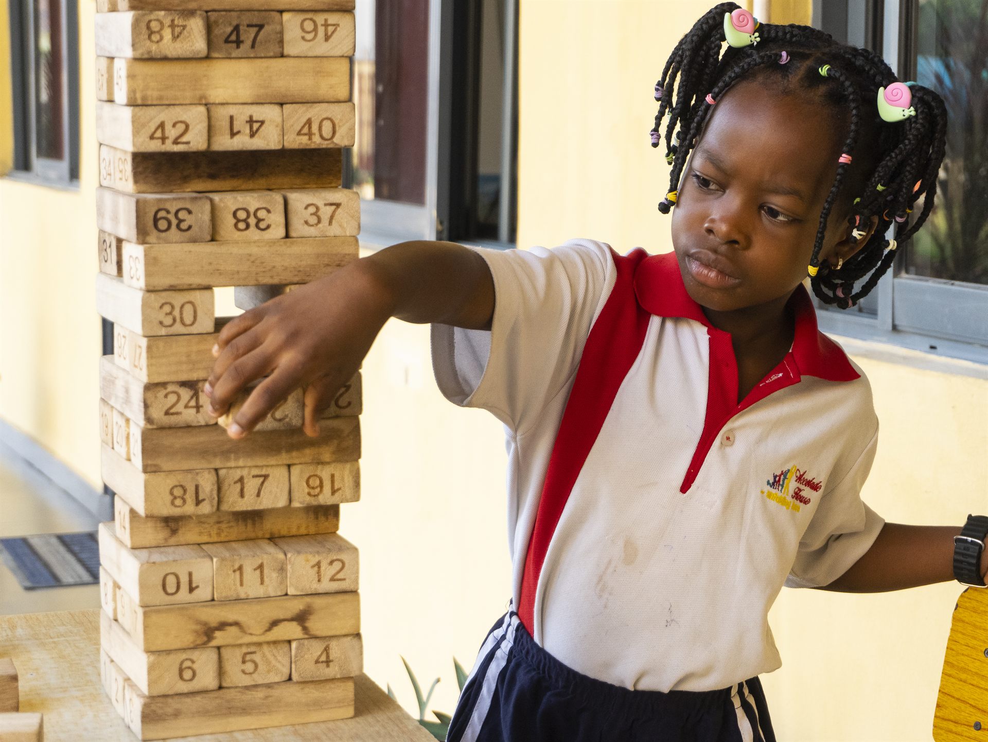An Accolade House pupil in school uniform playing with a building tower